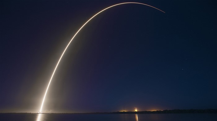 Rocket launch trail over water at night
