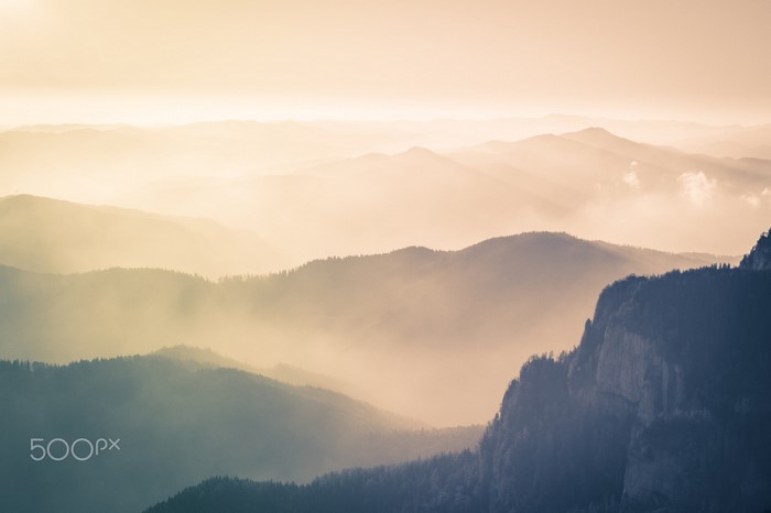 Misty mountain range at sunrise with sunlight