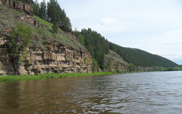 River flowing past a rocky cliff with trees