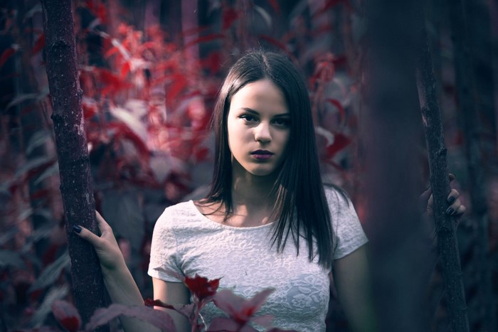 Woman in white top in a forest with red leaves