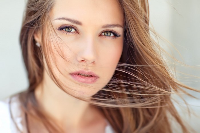 Close-up portrait of a young woman with long brown hair and green eyes