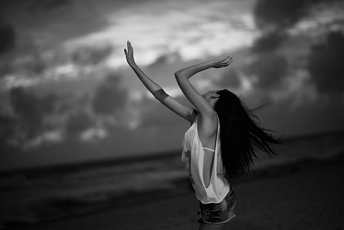 Woman with arms raised on a beach at dusk