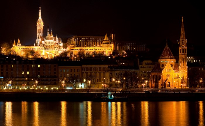 Budapest cityscape at night with illuminated buildings and river reflection