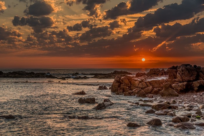 Sunset Over Rocky Seashore with Dramatic Clouds