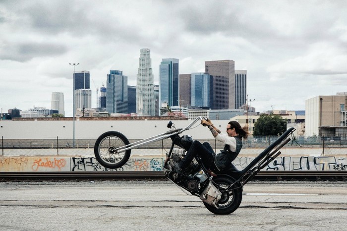 Man performing a wheelie on a custom chopper motorcycle in Los Angeles