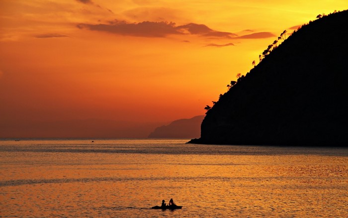 Kayakers on the sea at sunset with a silhouetted island