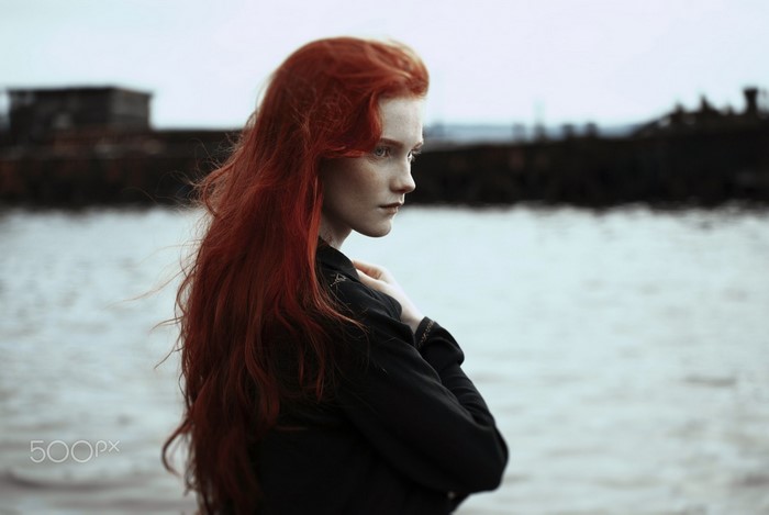 Woman with long red hair by the water