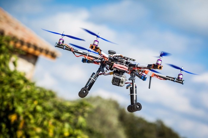 Drone with camera flying near trees and house