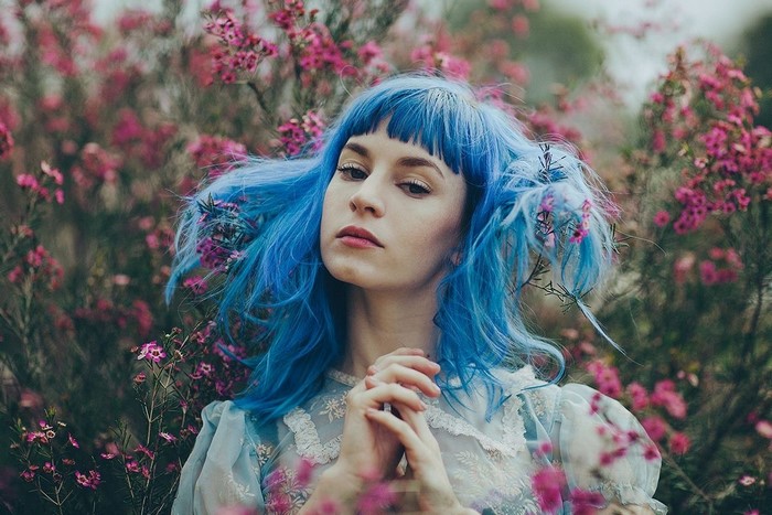 Woman with blue dyed hair among pink flowers
