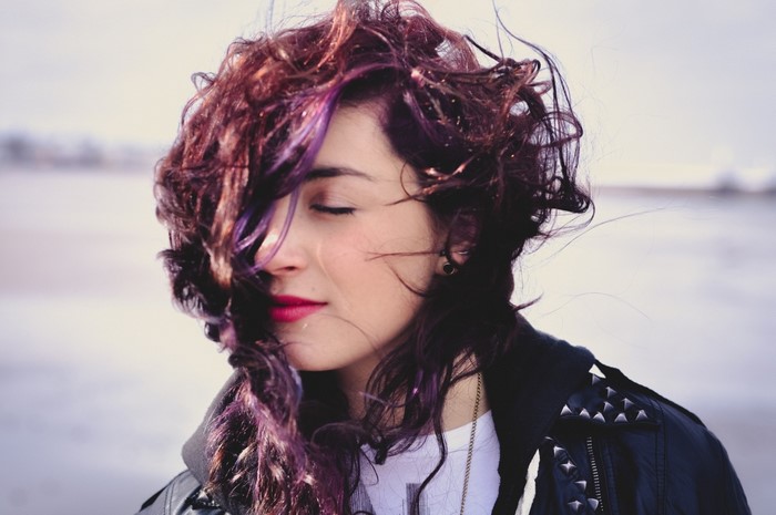 Woman with purple dyed wavy hair wearing a leather jacket
