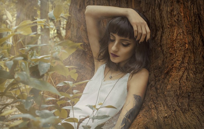 Woman leaning against a tree in a forest