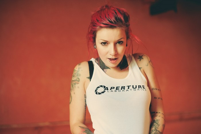 Woman with red hair and tattoos wearing Aperture Laboratories shirt