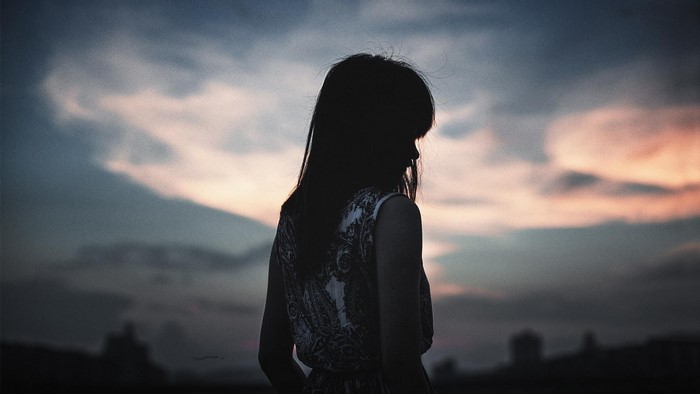 Silhouette of a woman against a sunset sky