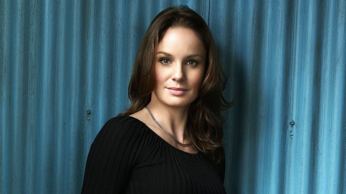 Woman with long brown hair wearing a black top
