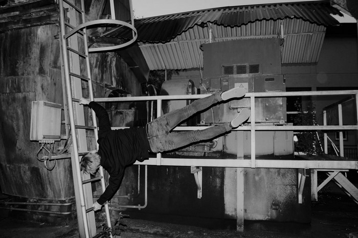 Person performing human flag on industrial ladder
