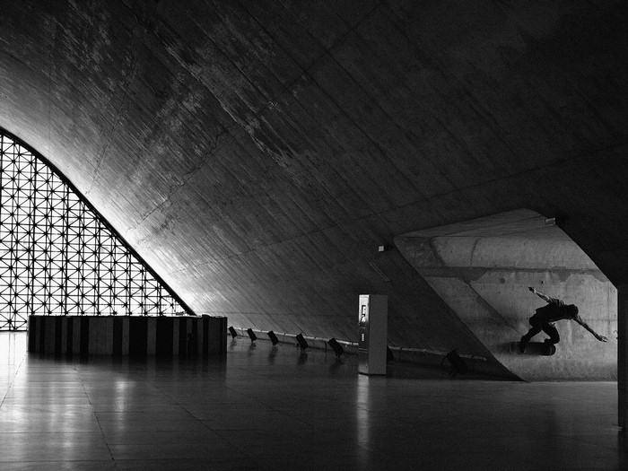 Skateboarder in a concrete building with geometric window