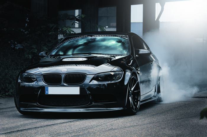 Black BMW M3 performing a burnout with smoke