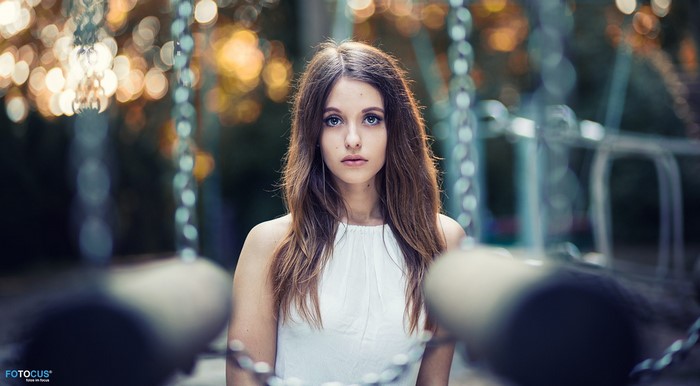 Woman in white dress looking at viewer with bokeh background
