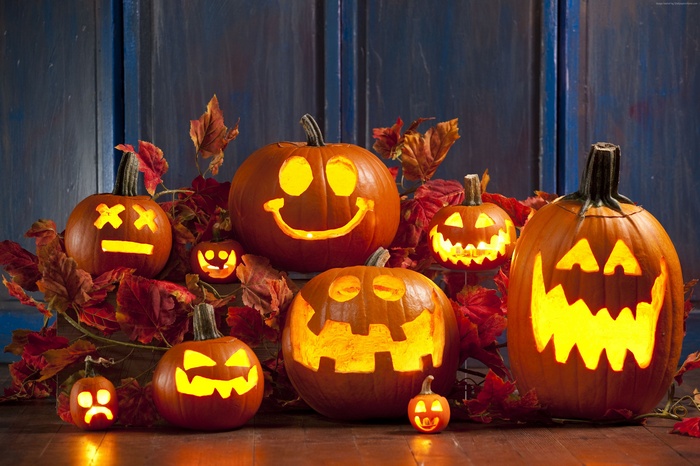 Halloween pumpkins with carved faces and autumn leaves