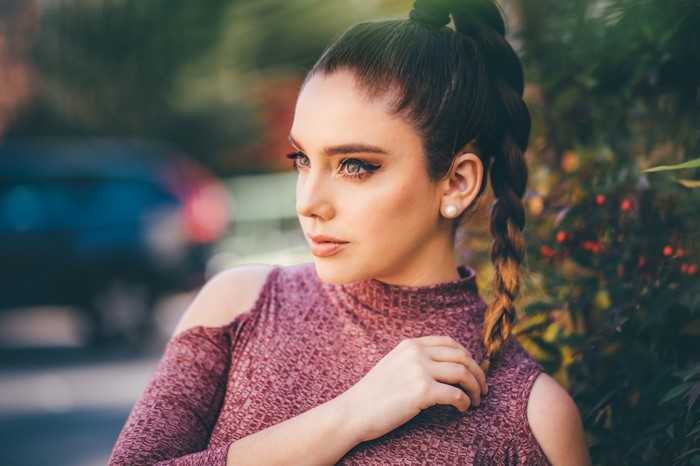 Woman with braided hair and pearl earring outdoors