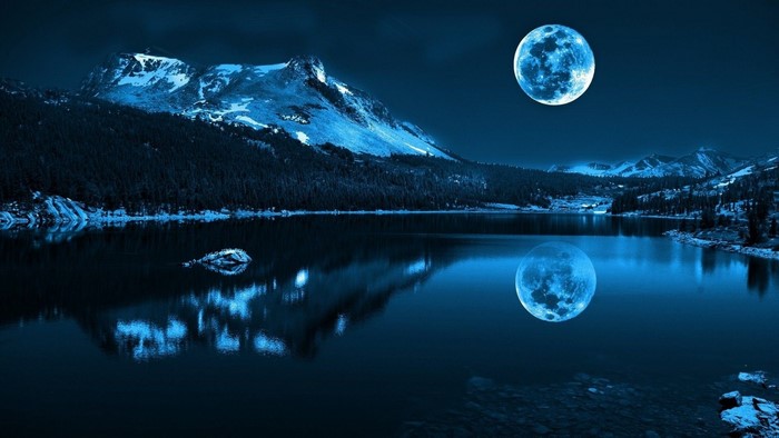 Full moon over a lake and mountains at night