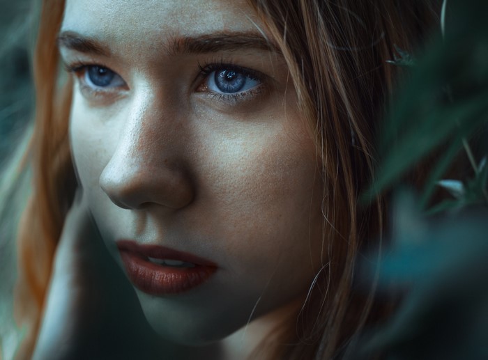 Close-up portrait of a young woman with blue eyes and freckles