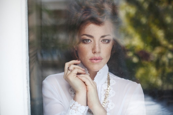 Woman with freckles looking through glass