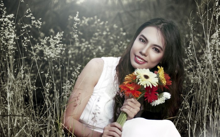Woman holding a bouquet of gerbera daisies in a field