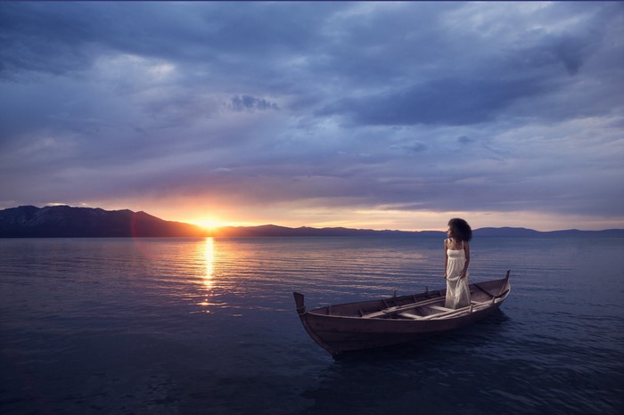 Woman in a boat at sunset over the sea