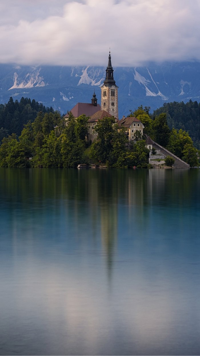 Church on an island in a lake with mountains