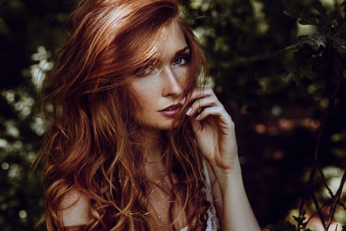 Woman with long wavy red hair in a forest