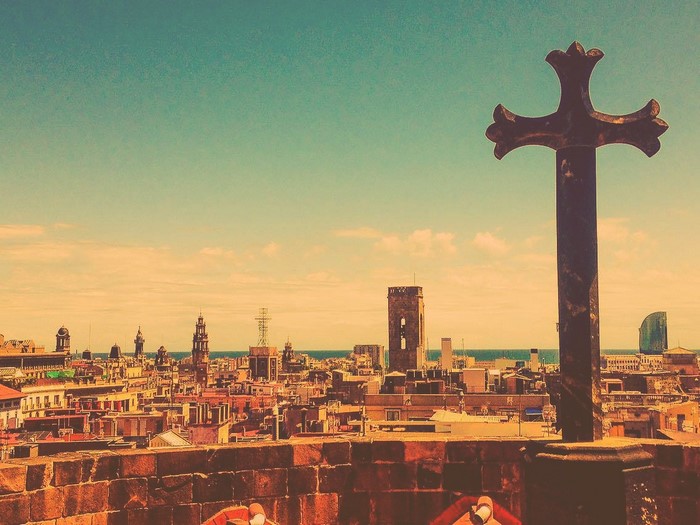 Cross overlooking Barcelona cityscape at sunset