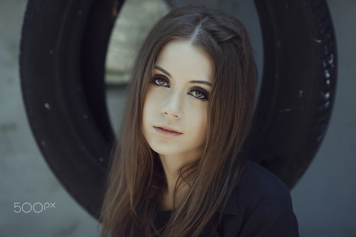 Woman with long brown hair in front of a tire