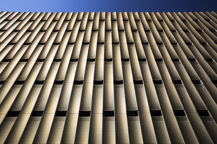 Modern building facade with repeating patterns and blue sky