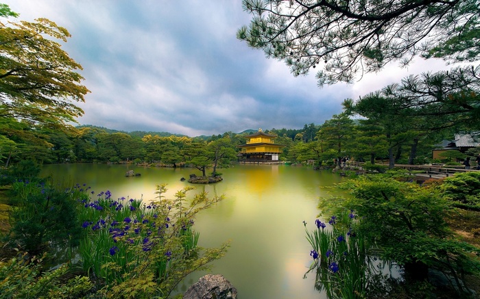 Golden Pavilion reflected in a pond with surrounding trees and flowers