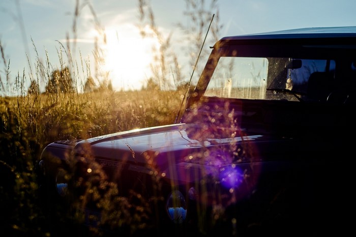 Car in a field at sunset with lens flare