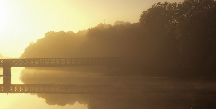 Bridge over misty river at sunrise