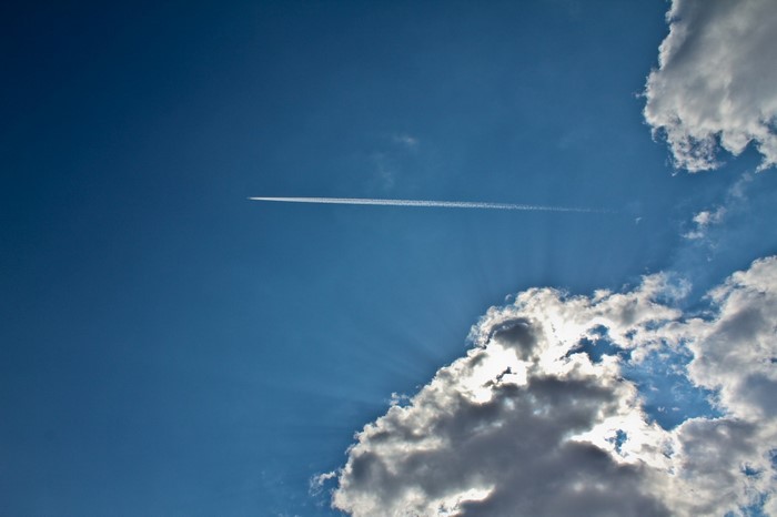 Airplane contrail in a blue sky with clouds
