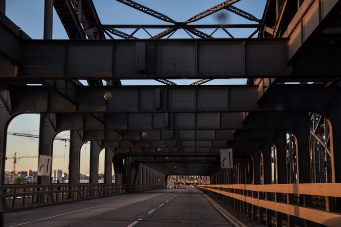 Steel bridge structure over a road with city in background