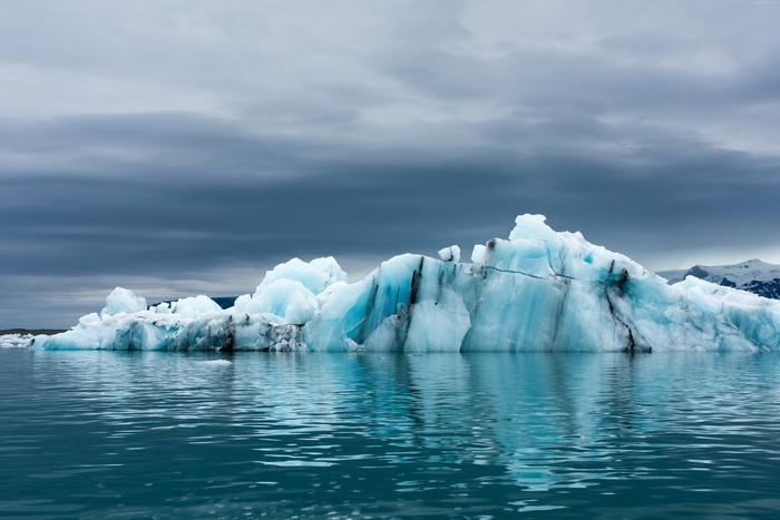 Iceberg floating in the ocean under a cloudy sky