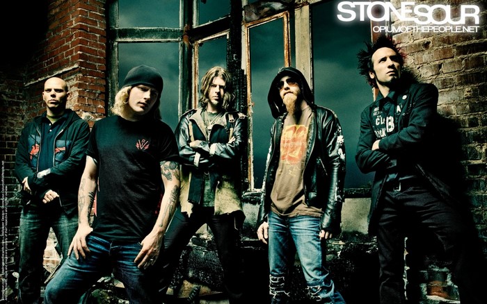 Stone Sour band members posing in front of a derelict building