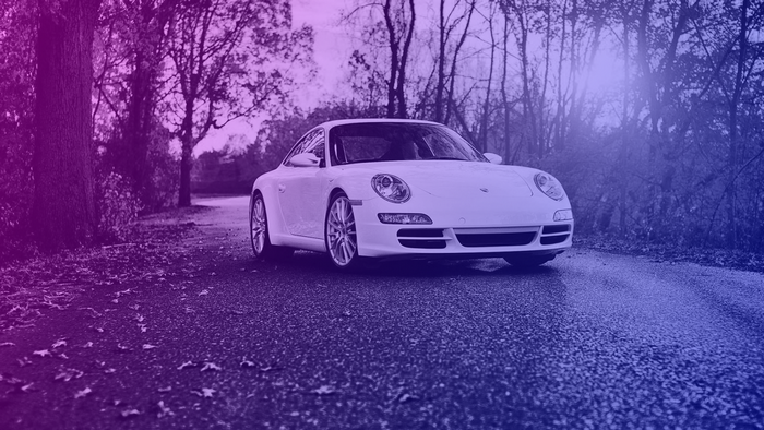 White Porsche sports car on a road with trees