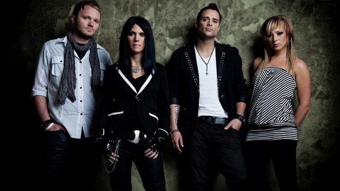 Skillet band members posing against a textured wall