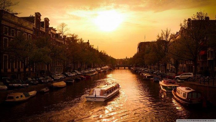 Amsterdam canal at sunset with a tour boat
