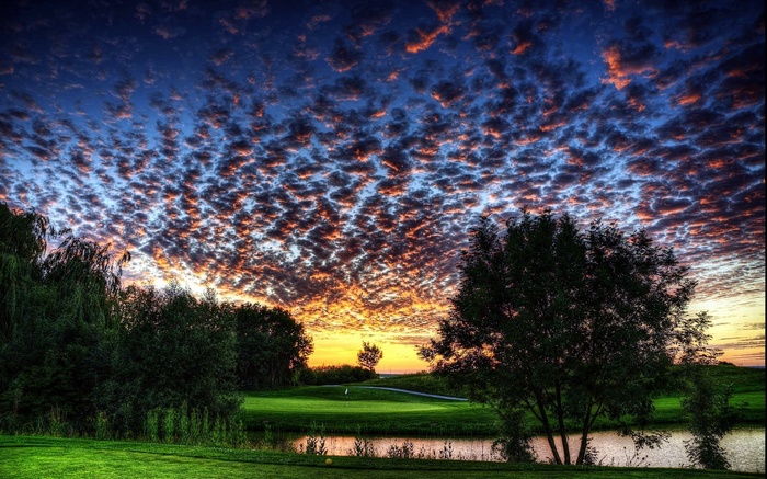 Dramatic sunset over a golf course with scattered clouds