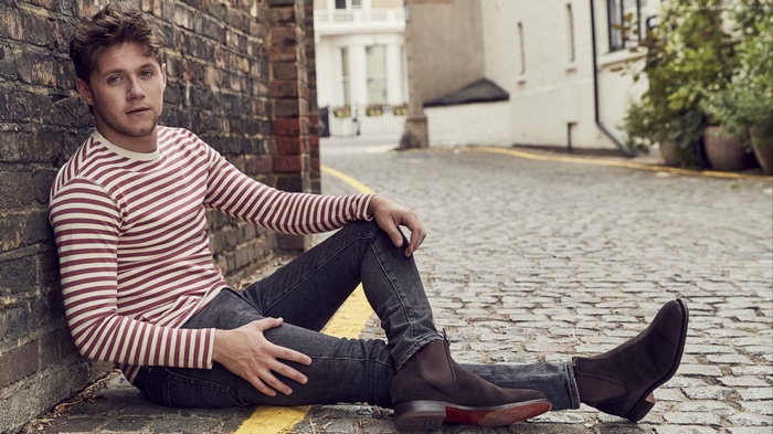 Niall Horan sitting on cobblestone street