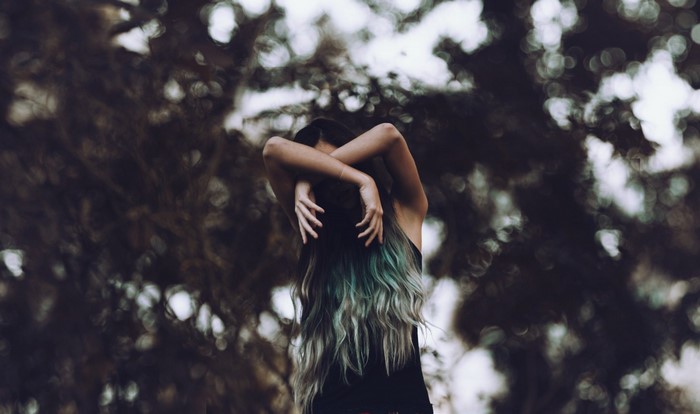Woman with blue-green hair in forest