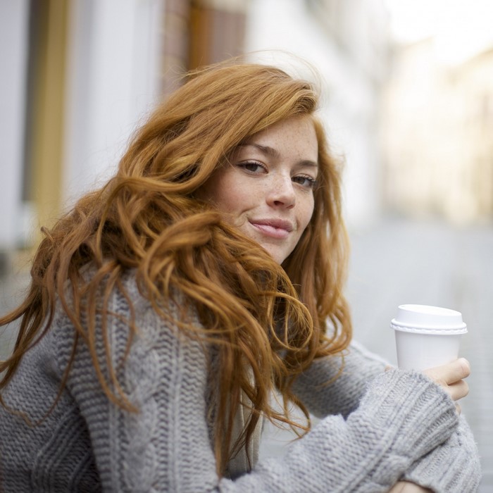Woman with red hair and freckles holding a coffee cup