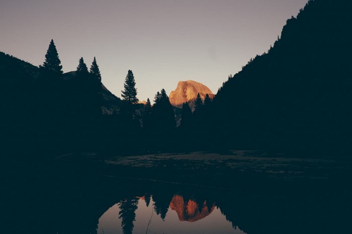 Half Dome mountain reflected in a lake at sunrise