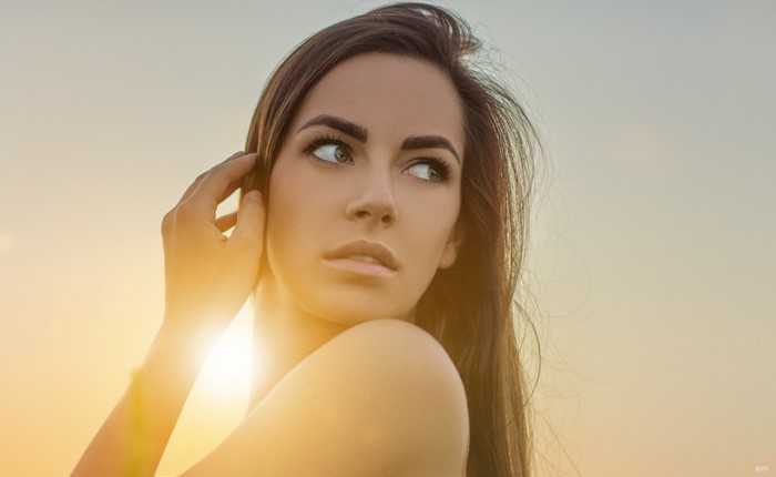 Woman with long brown hair looking away at sunset